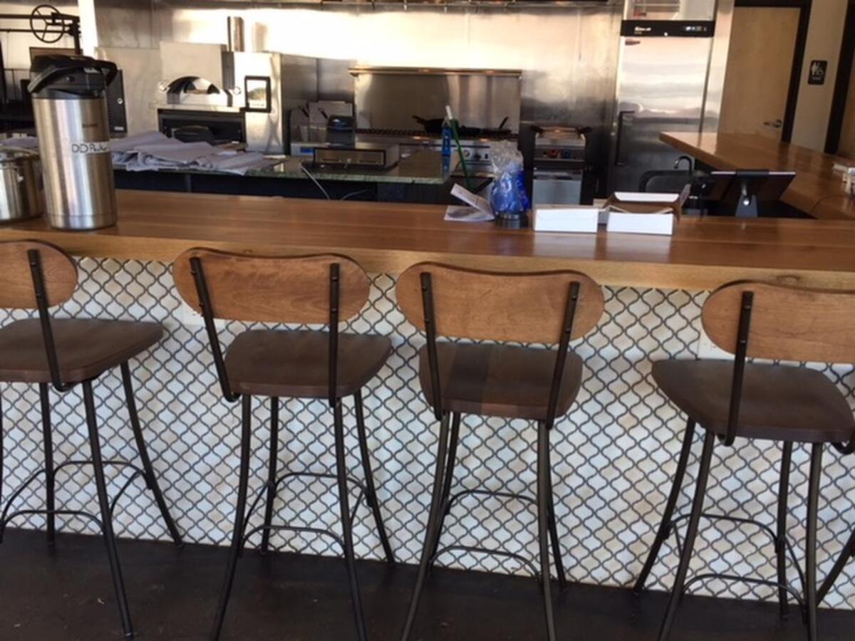 All the tables and bar chairs are uncovered and ready to go around Flourshop’s tiled bar.