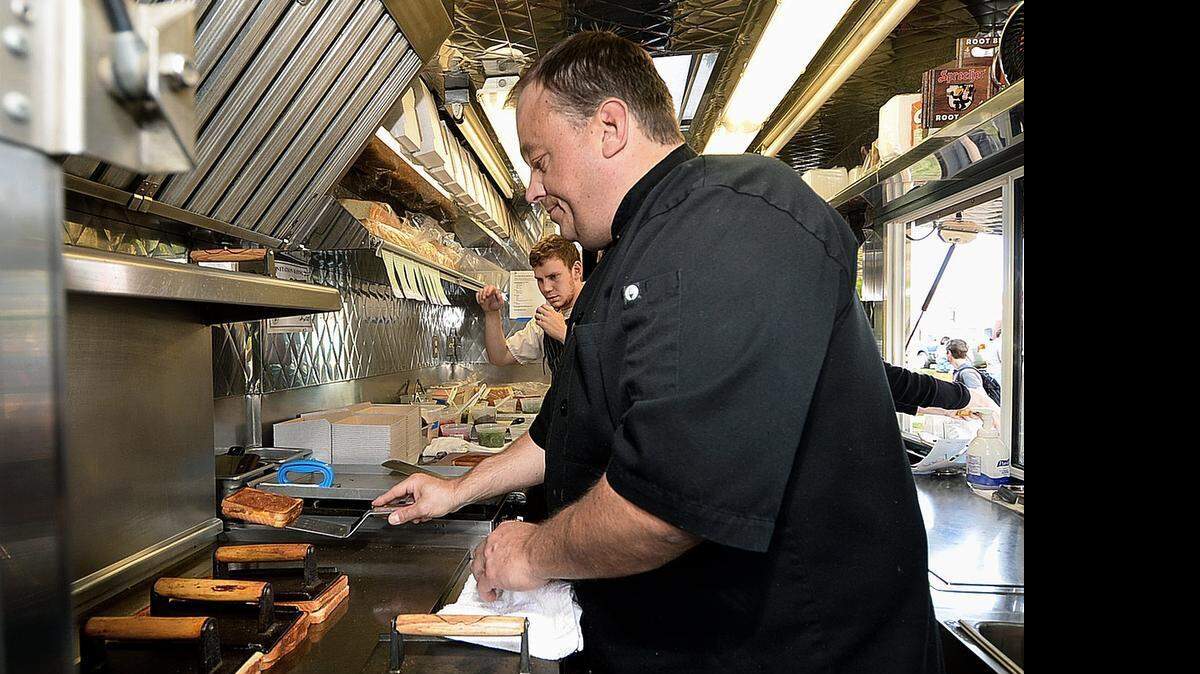 
Brian Stockholm, front, at work making grilled cheese sandwiches in his food truck Papi Queso, which he began operating in September 2012, featuring a variety of grilled cheese sandwiches. Much like his grilled cheese sandwich creations that represent a melding together of the past and future, Stockholm's food truck reflects the culinary path he took to opening Papi Queso. It combines his years of cooking school and his eclectic restaurant experience, both in the kitchen and the front of the house, with his need to carve out a fresh start and do things on his own terms.
