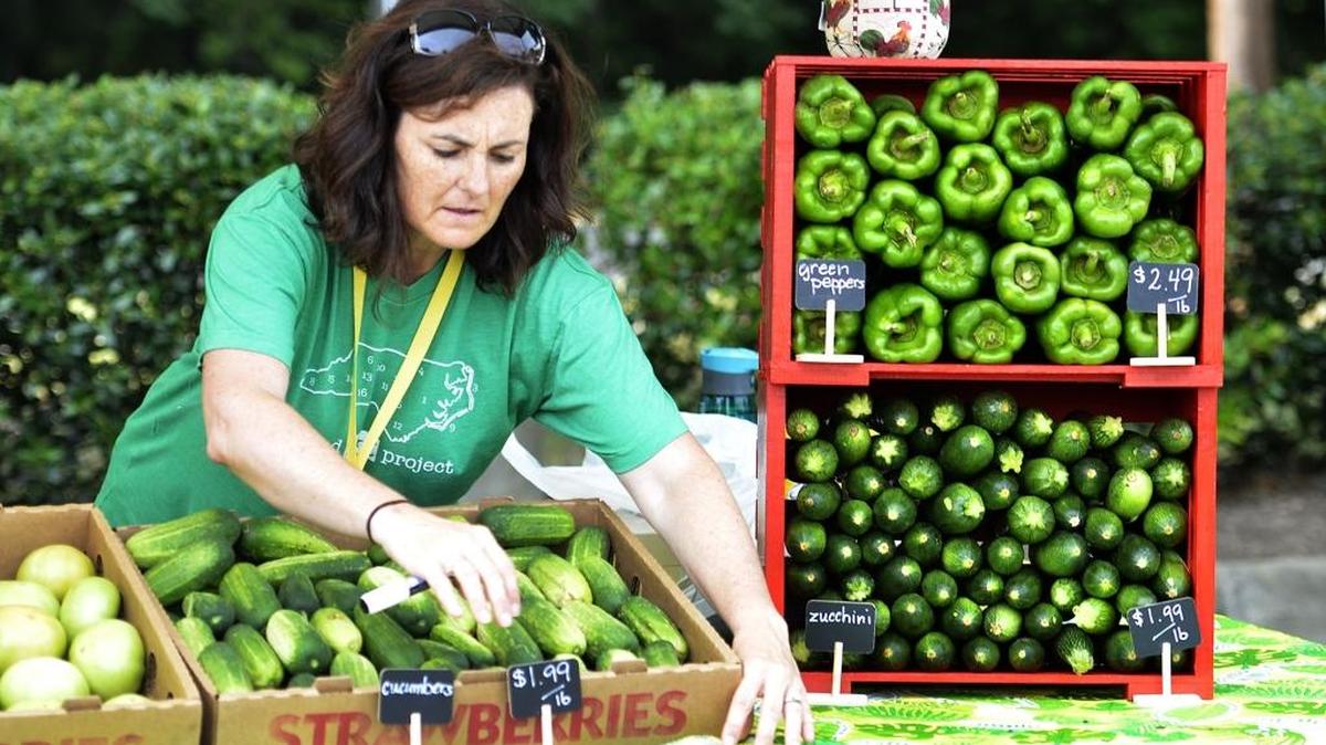 Shannon Hart, with Shady Oaks Farm, prepares her booth during the grand opening of the Rosa Parks Farmer's Market Tuesday. The Rosa Parks Farmer's Market held its grand opening on Tuesday, June 21, 2016 in the parking lot the the Mecklenburg County Northwest Health Department.