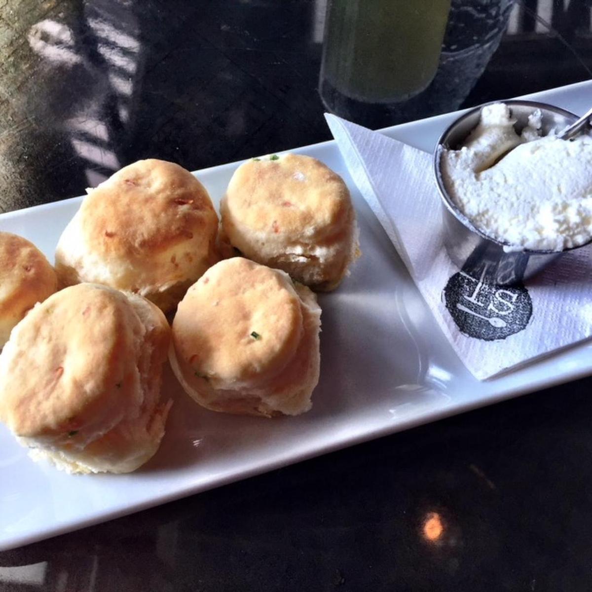 Mini biscuits with flecks of cheese and jalapenos are served with a little dish of bacon fat butter made from beaten fat and heavy cream.