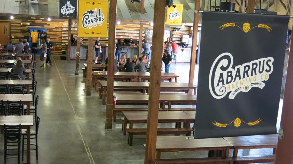 Cabarrus Brewing Co.’s 15,000-square-foot building can hold just north of 600, and with its communal seating resembles a German beer hall. They’ve retained much of the building’s industrial nature by using lumber and tin from around the mill property to build the bar and other features.
