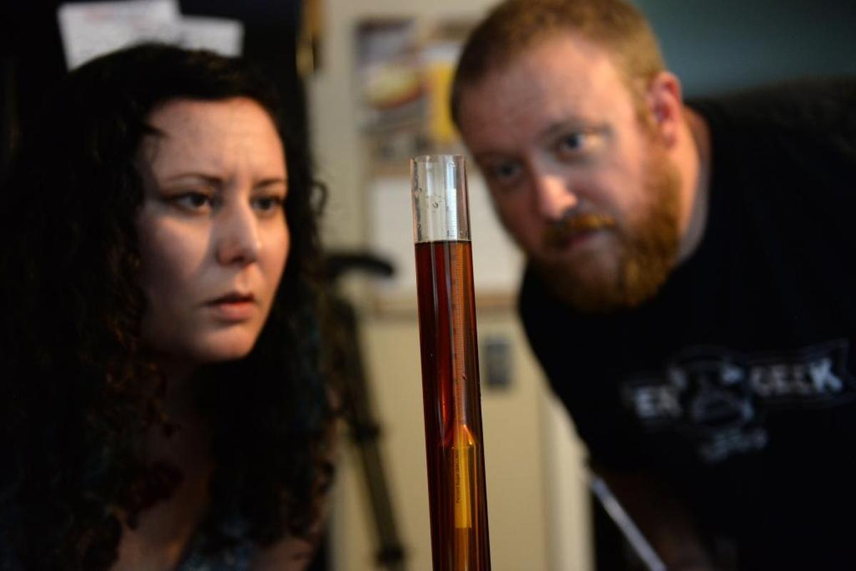 Jen Blair and her husband, Tom Crast, both home brewers, test the gravity, the density compared to water, of their homemade barley wine. By checking the gravity before and after the fermentation process, they can determine the beer’s alcohol content