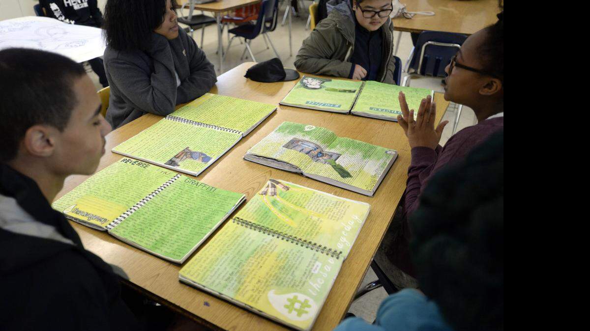 
Members of the West Charlotte High IB Art 3 class sit with their idea books open last month as a group makes a  presentation during class.
