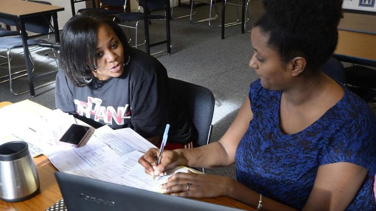 In this photo from 2015, Gelila Selassie (right) assists a customer in signing up for health insurance through the online marketplace during an event at Legal Services Southern Piedmont.