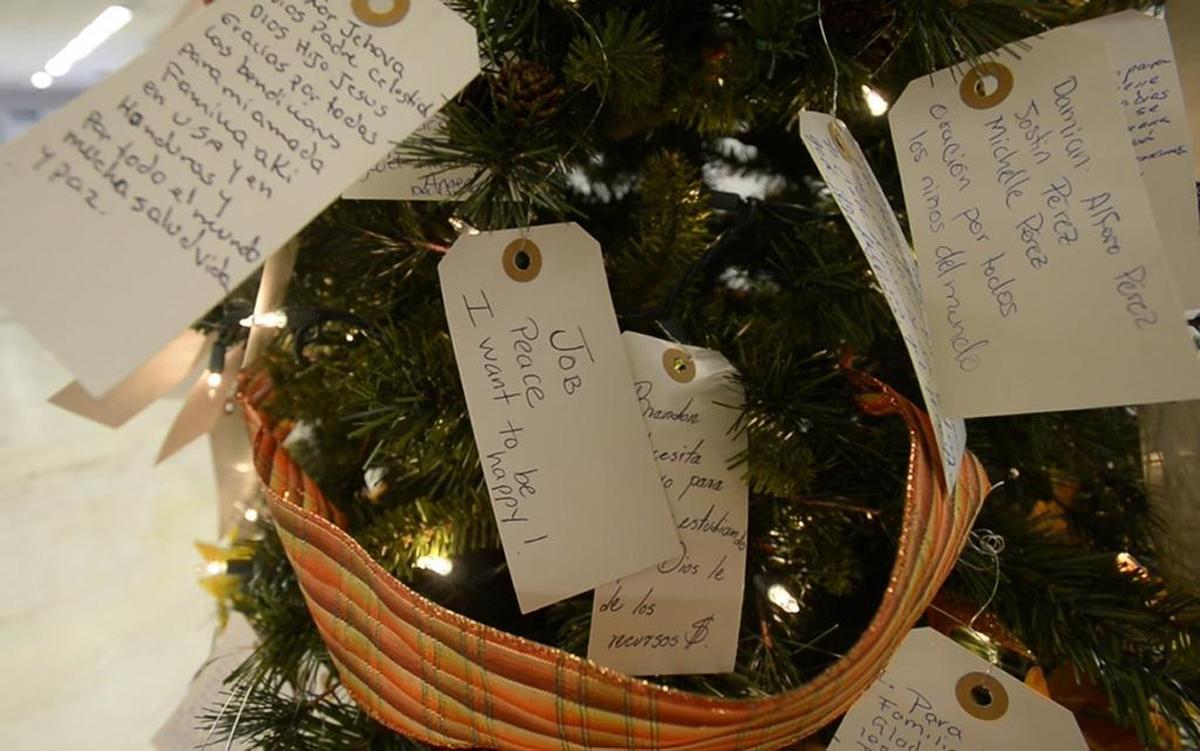 Tags with prayers are hung on a prayer tree at the Salvation Army's Christmas Bureau. The tag on the left reads: “God in heaven, thank you for all of the blessings for my loving family here in the U.S. and in Honduras, and for all the world, much health, life and peace.”