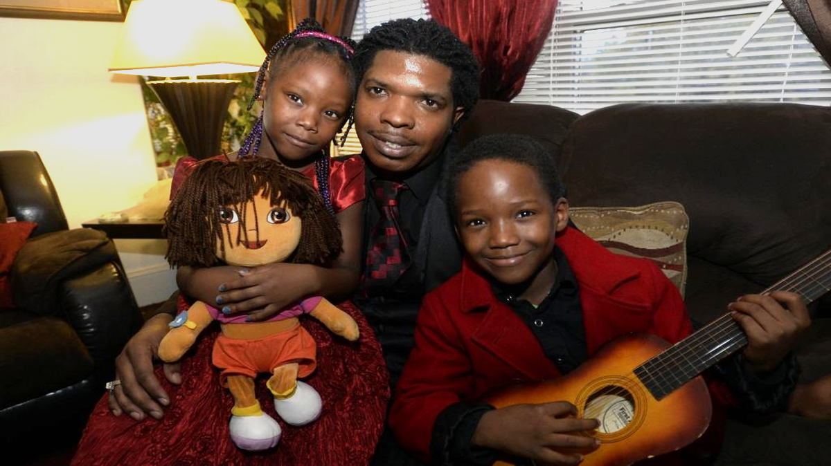 Octavious Young holds onto his niece and nephew, Keanyada, 6, and Xzabeon, 9, who he is raising for his sister, in their home in Charlotte on Wednesday, November 18, 2015.