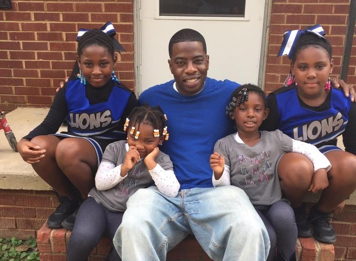 Travis Thompson, center, sits on the stoop of the home where he’s raising two sets of twin daughters. They are Daziah, top left, Danasia, top right, Dynasty, bottom left, and Destiny, bottom right.