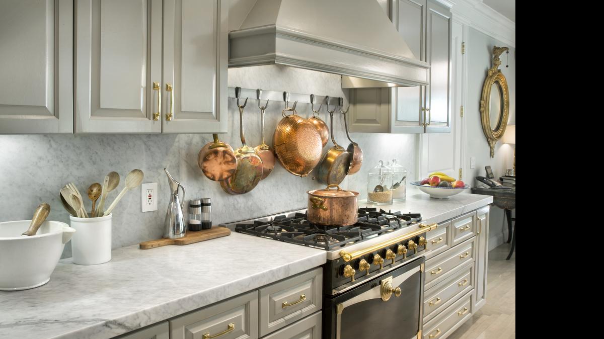 
A well-planned design can incorporate more than one color of metal. The cooper cookware collection suspended from a stainless steel bar brings a glow that works with the brass hardware. 
