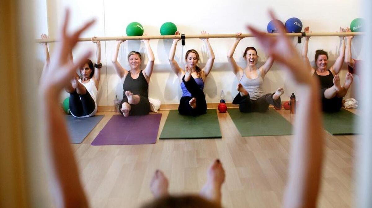 Pilates class-goers share a laugh while working their cores.