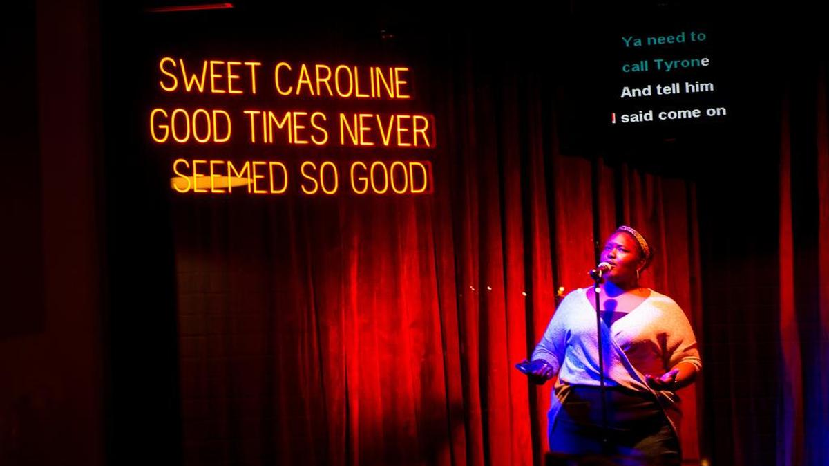 The karaoke room at 8.2.0 features a neon sign with the lyrics to “Sweet Caroline.”