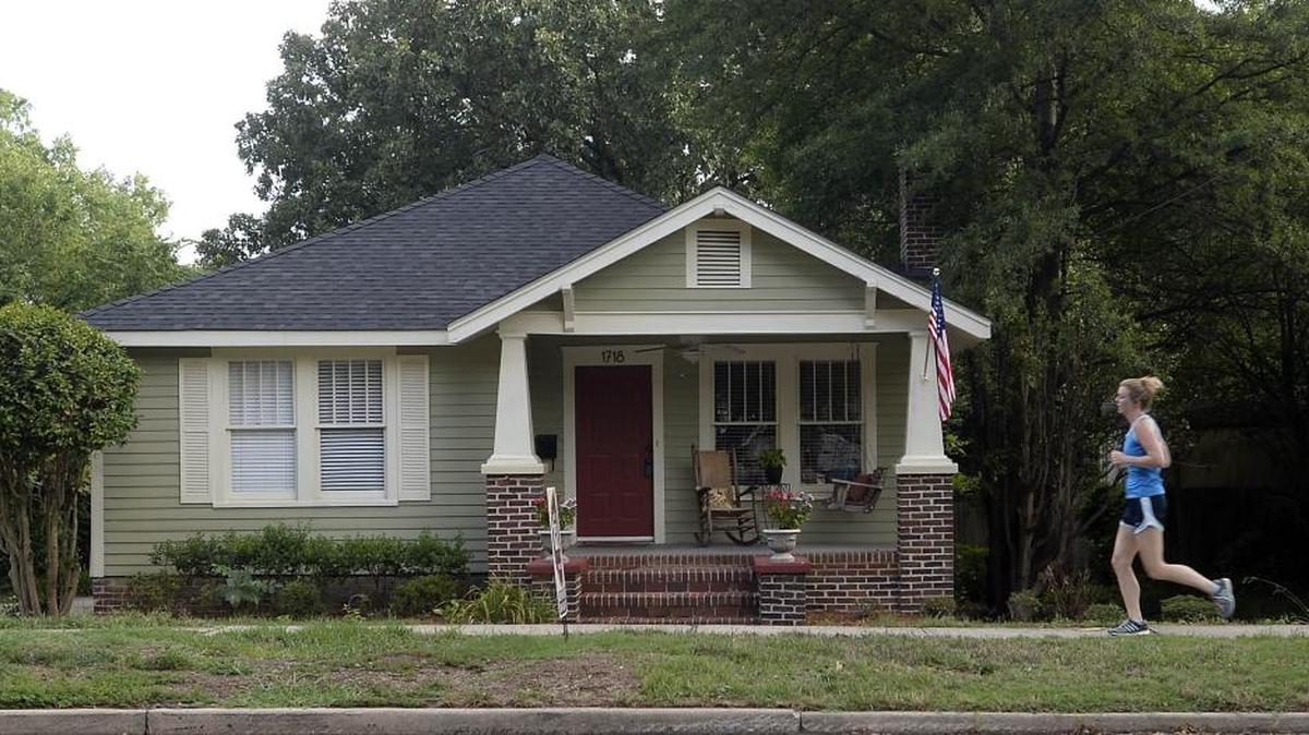 A jogger passes a home in Plaza Midwood. Realtors say the region remains extremely attractive to buyers.