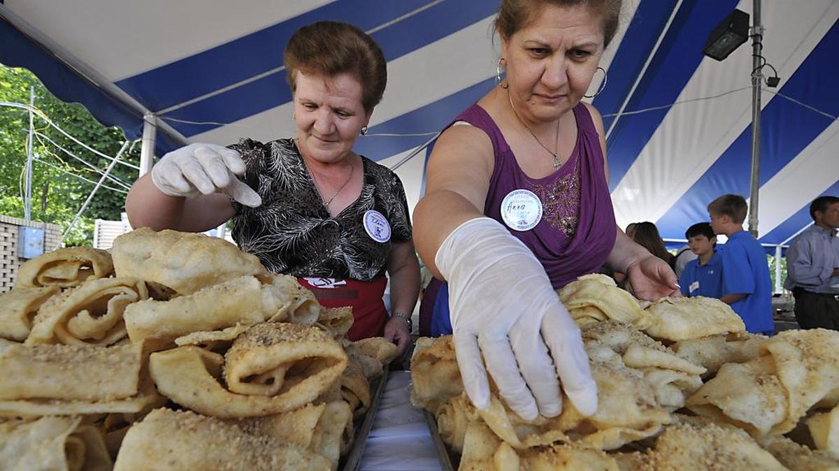 Eleni Bisbikis (left) and Anna Sohoritis stack fresh greek pastry “diples” on the tray during the lunch hour rush at a past Yiasou Greek Festival.