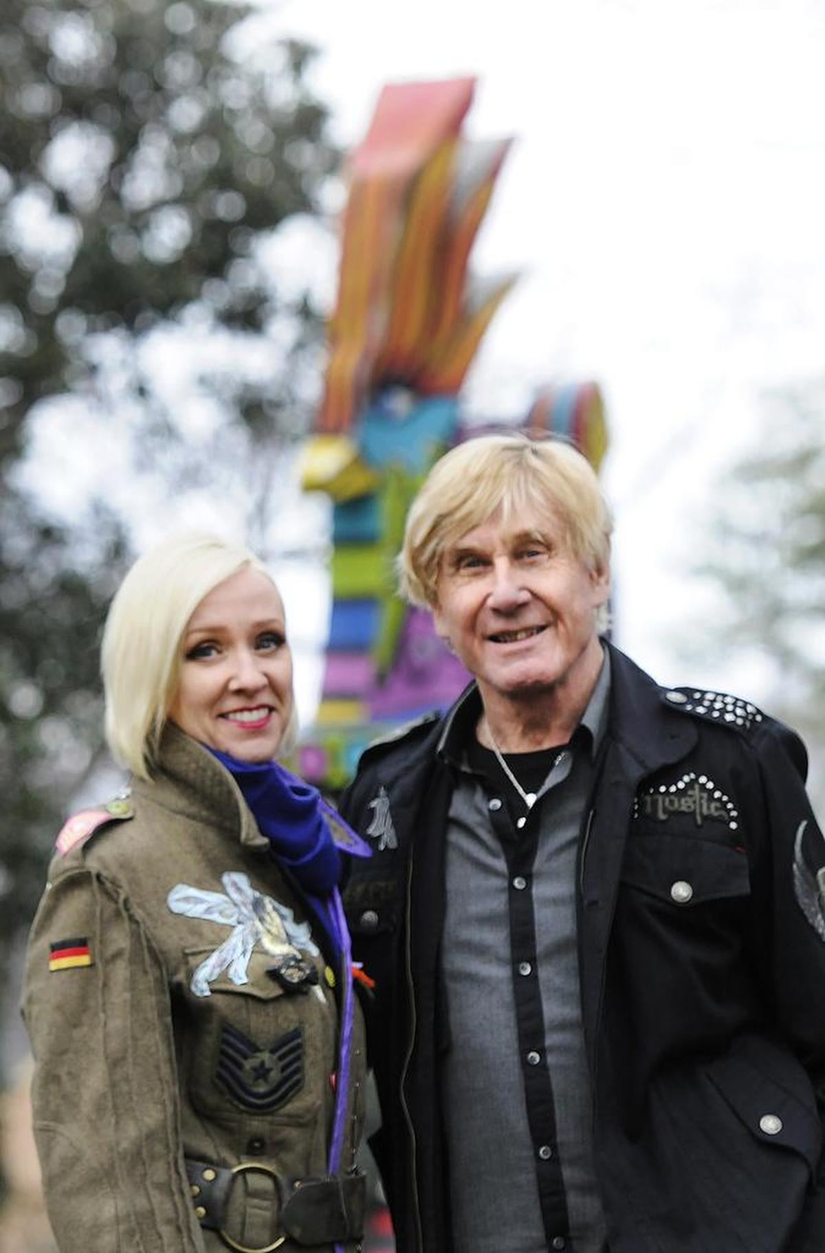 Regine and Andreas Bechtler pose in front of a multicolored sculpture of a chicken that stands about 25 feet tall in their Charlotte front yard.