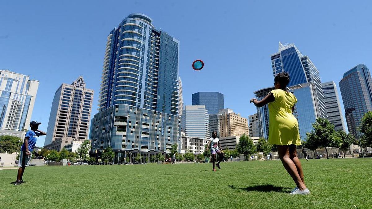 DJ Brown, 12, left, sister Aliyah Brown, 10, back center, and mother Ayanna Brown, right, throw a frisbee at Romare Bearden Park.