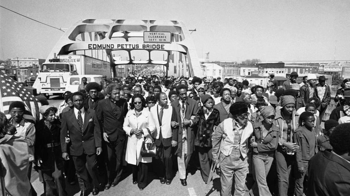 Aided by Father James Robinson, Mrs. Coretta Scott King, widow of Dr. Martin Luther King, Jr., center, and John Lewis of the Voter Education Project, a crowd estimated by police at 5,000, march across the Edmund Pettus Bridge from Selma, Alabama Saturday, March 8, 1975. The march commemorated the decade since the violent struggle for voting rights began in 1965 with “Bloody Sunday” at the bridge as police tried to stop a march to Montgomery.