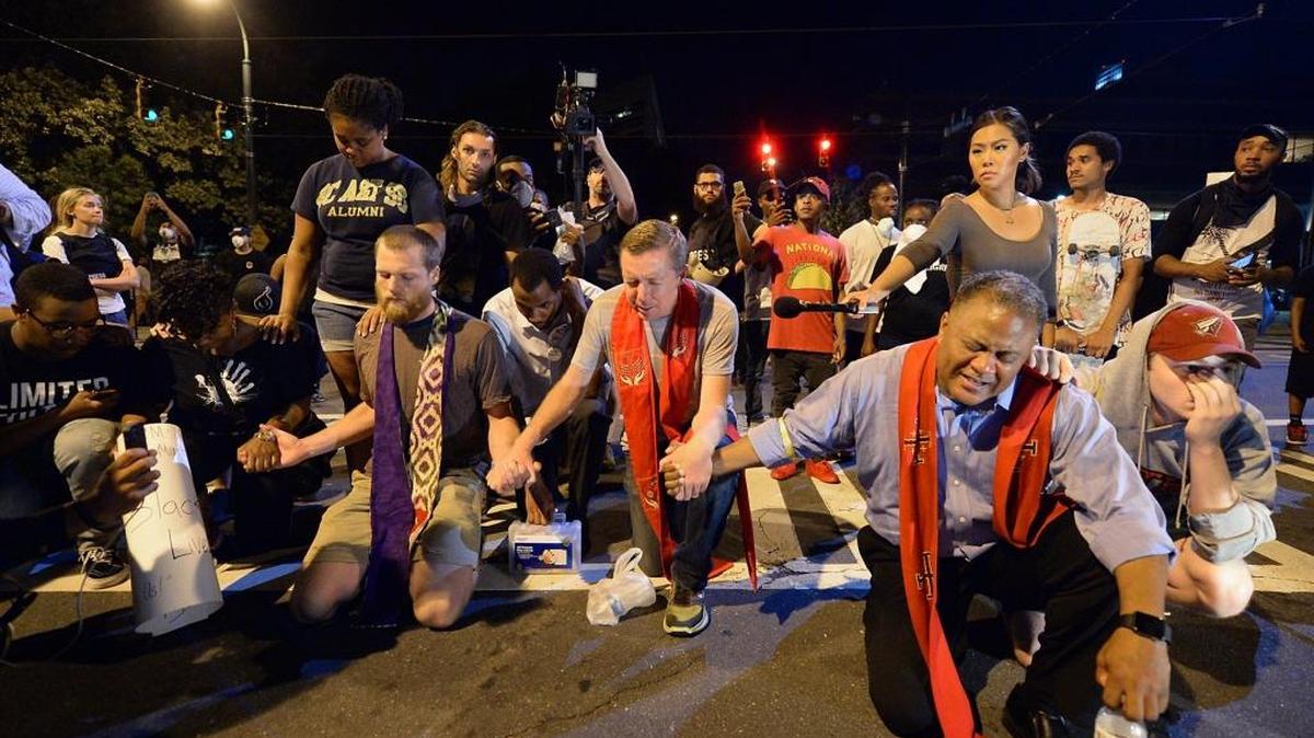 Clergy prayed with protesters outside the Charlotte Mecklenburg Police Department last September. Protesters came together for the fifth straight night to protest following the fatal shooting of Keith Lamont Scott by police. On Wednesday, many of the same clergy will march in memory of the deaths of Scott and Justin Carr and of the protests.