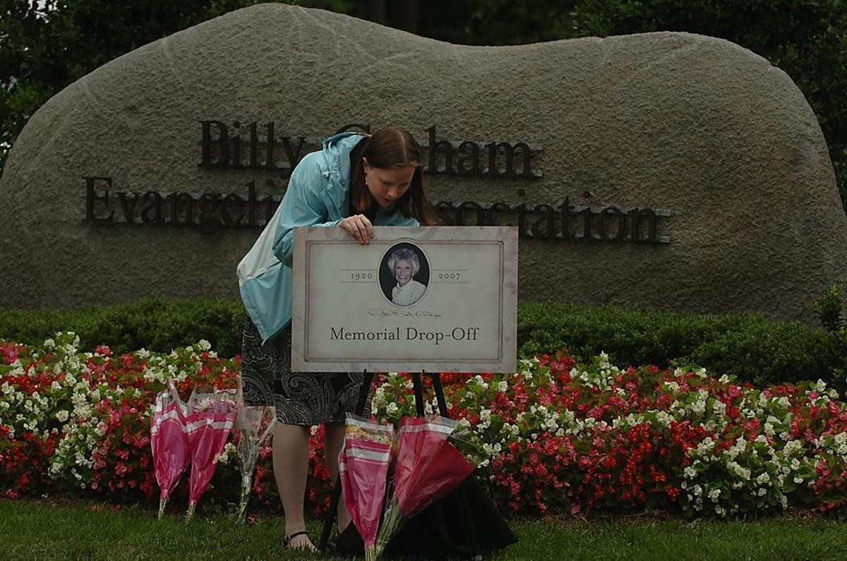 In June 2007, Laura Cochran, an employee with the Billy Graham Evangelistic Association, arranges flowers and a memorial drop-off sign at the entrance of the Billy Graham Library in Charlotte the day after Ruth Graham died.