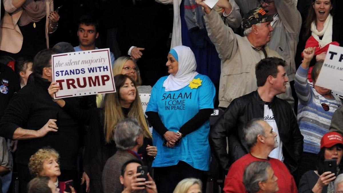 Rose Hamid, center, stands in silence as Donald Trump speaks of radical Islam and terrorism during the Donald J. Trump for President rally at the Winthrop University Coliseum in Rock Hill, S.C. on Jan. 8, 2016. As an officer escorted her to an exit, several supporters jeered her. “One man said: ‘Do you have a bomb?’ I said, ‘No, do you have a bomb?’ ” Hamid said