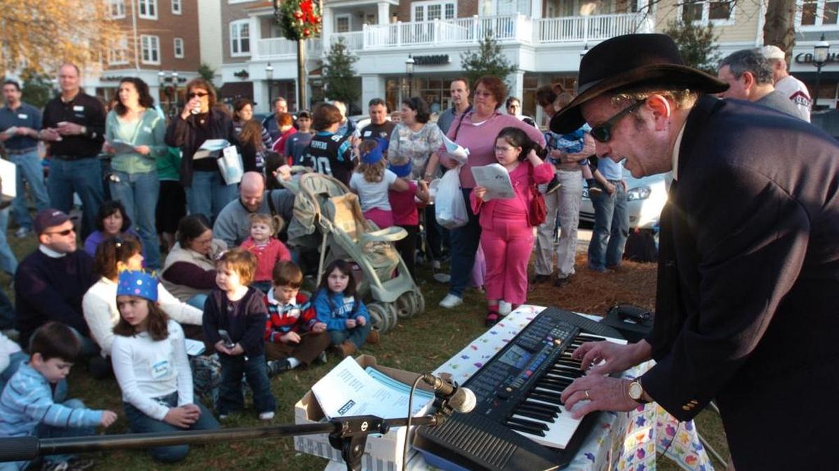 Cantor Elias Roochvarg, of Temple Israel, leads the singing of holiday songs at the Beth Shalom of Lake Norman’s Hannukkah Celebration at the Village Green at the Birkdale Shopping Center.
