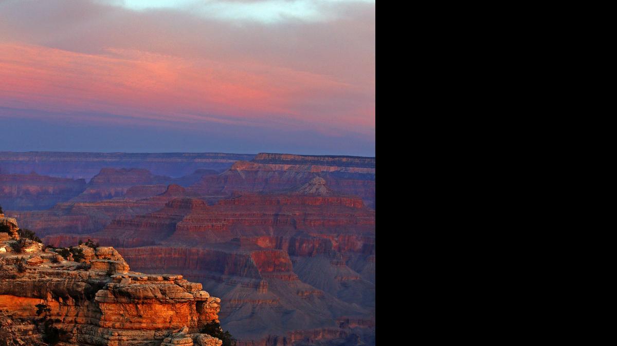 
The colors of dawn begin to paint the age-old rock formations along the South Rim near Mather Point.
