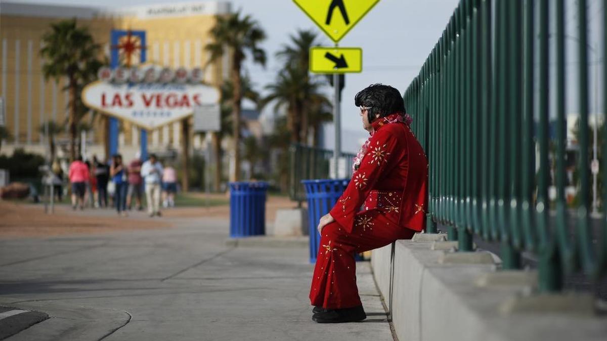 In this2016, photo, Ted Payne rests as he works for tips dressed as Elvis at the “Welcome to Las Vegas” sign in Las Vegas.
