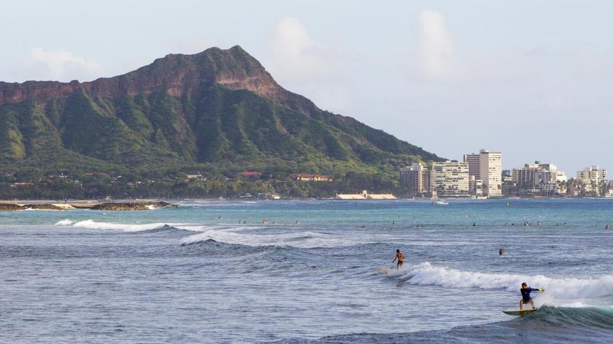 Surfers ride the waves off Ala Moana Beach Park, in Honolulu with Diamond Head mountain in the background. Diamond Head, a volcanic crater at one end of Waikiki, is one of Hawaii’s most famous landmarks.
