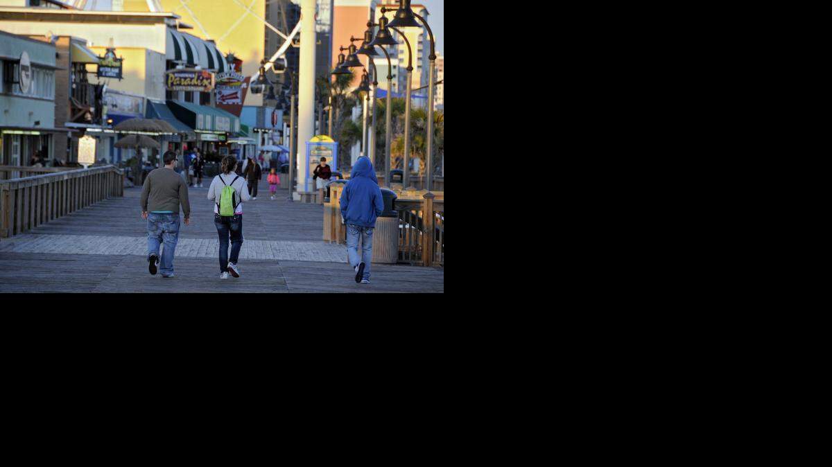 
People stroll the Myrtle Beach Boardwalk at sunset. 
