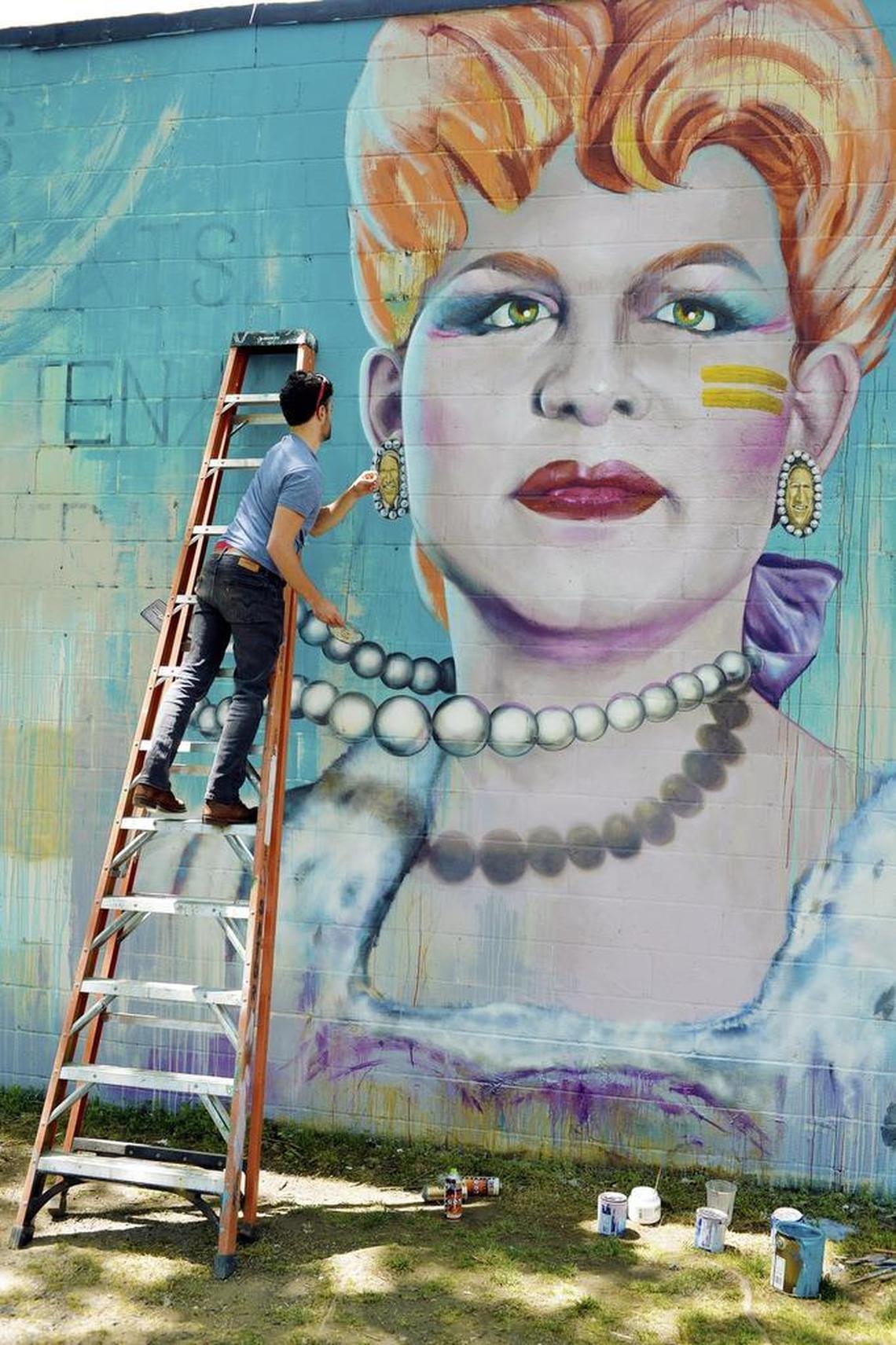 Artist Nick Napoletano touches up one of the earrings on the mural of Brandy Alexander, a drag queen pioneer.