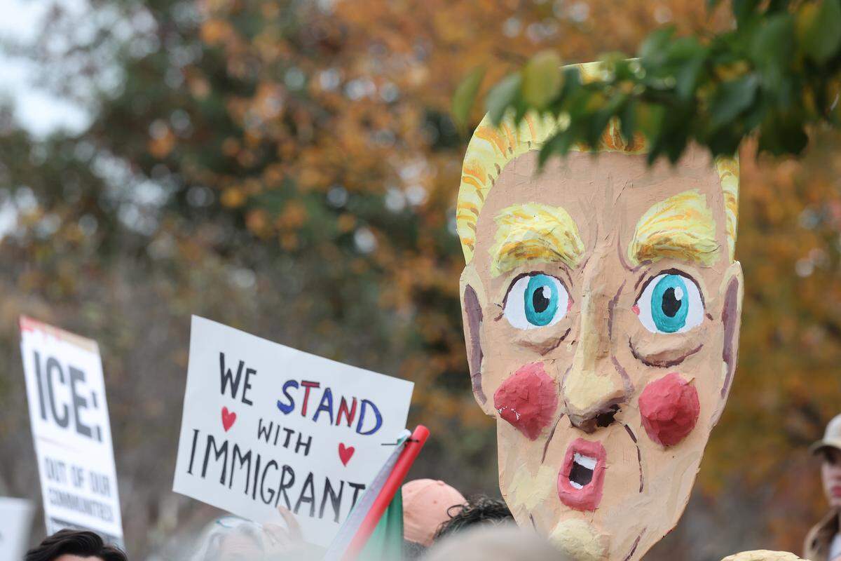 Protesters hold signs and a large image of President Trump Saturday at the No Border Patrol protest in uptown Charlotte.