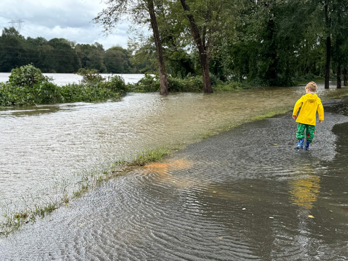 7-year-old Harlan Culberson walks along a flooded path beside the Catawba River Friday as the river overflowed its banks.