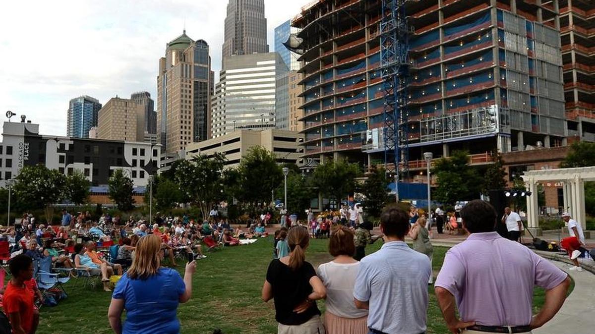 The growing skyline of Charlotte, NC provides a backdrop as spectators listen to the band Flashback at Romare Bearden Park on July 6, 2016. Visitor spending hit record highs in the Charlotte region last year, according to a new study.
