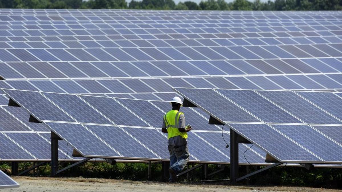 A worker walks among a set of solar panels at an O2 Energies solar farm in Montgomery County.