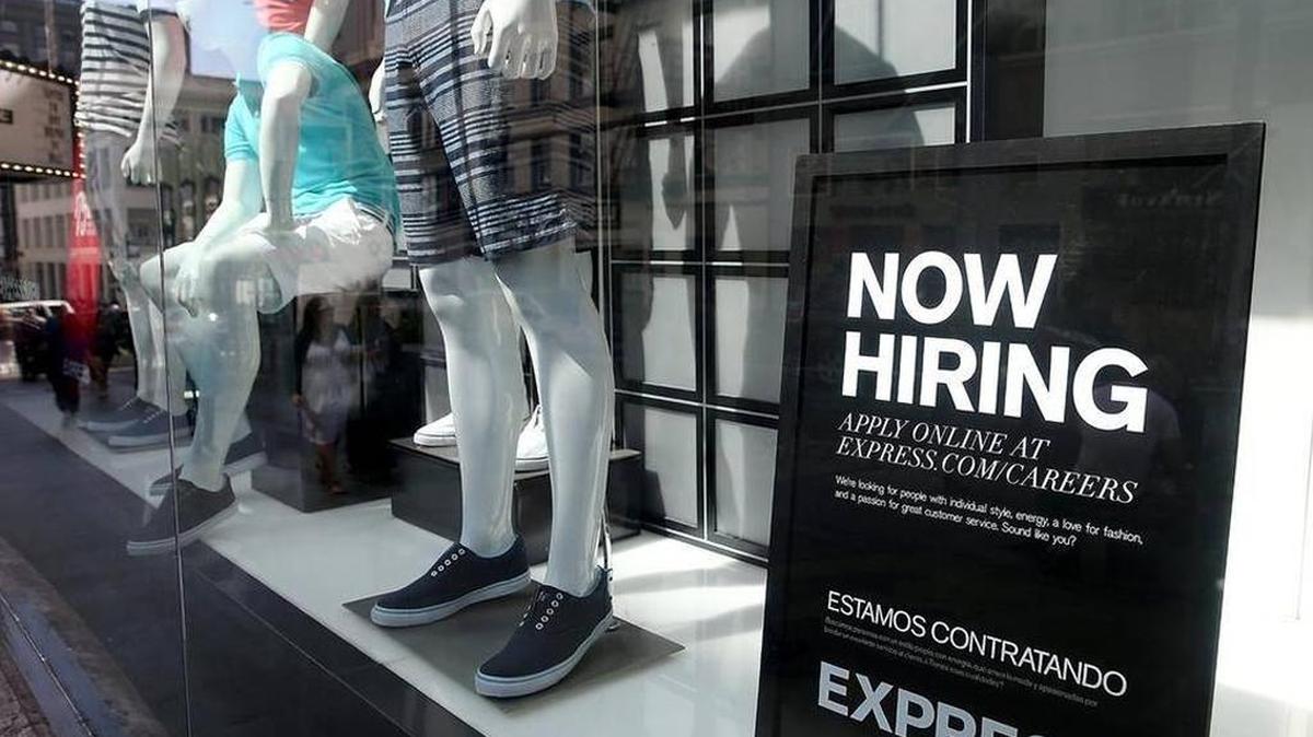 A now hiring sign is posted in the an Express store