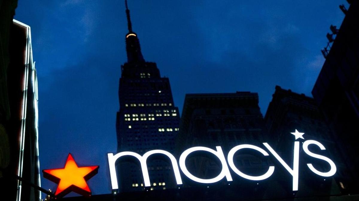 FILE - In this Nov. 21, 2013, file photo, with the Empire State building in the background, the Macy's logo is illuminated on the front of the department store in New York.