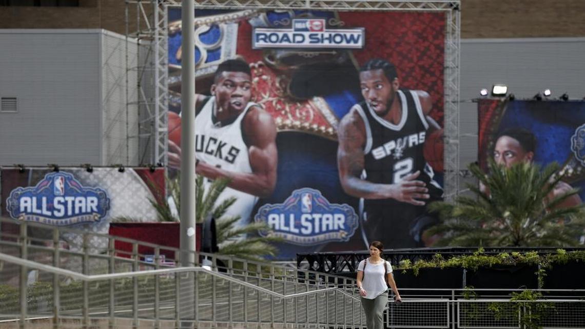 Rachel Seibel walks past signs being put up for the NBA All-Star Game festivities this weekend in New Orleans.