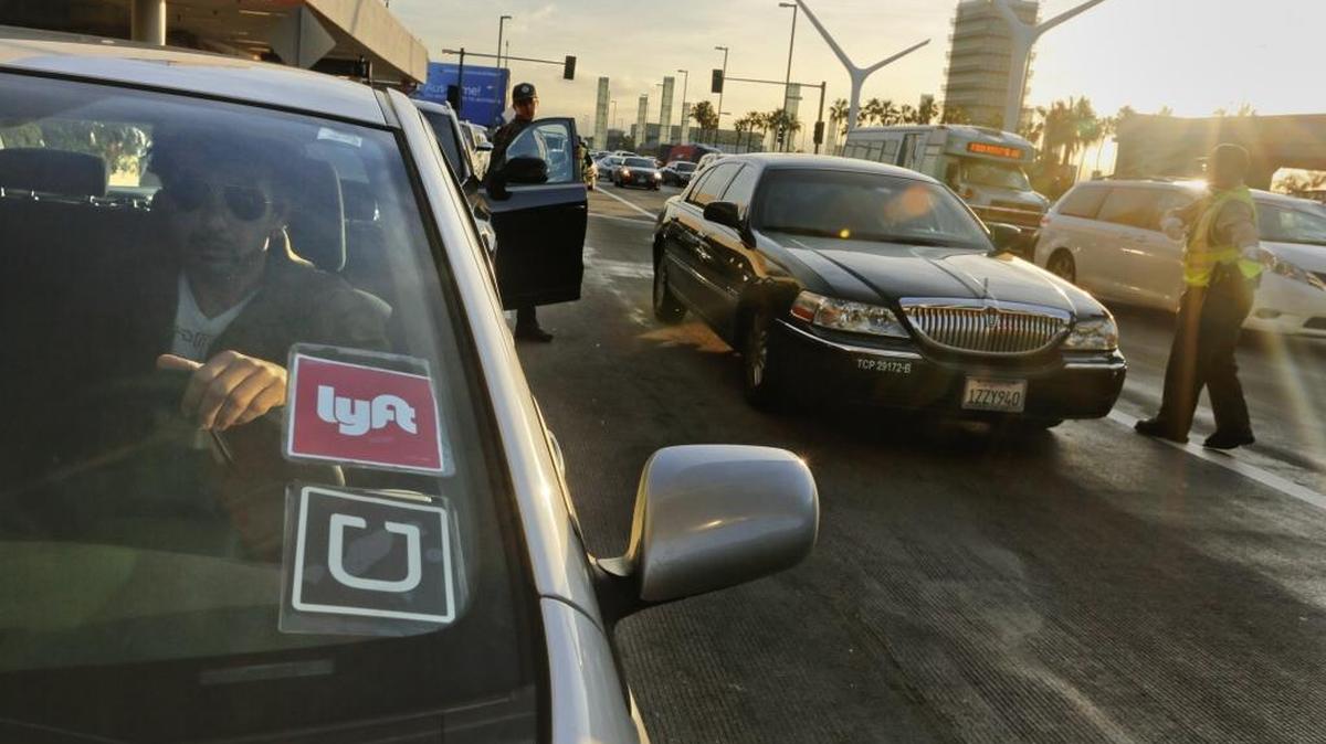 Many of the Lyft drivers are also doubling their efforts as Uber drivers as they drop off riders in front of Terminal 1 at Los Angeles International Airport on Dec. 23, 2015.