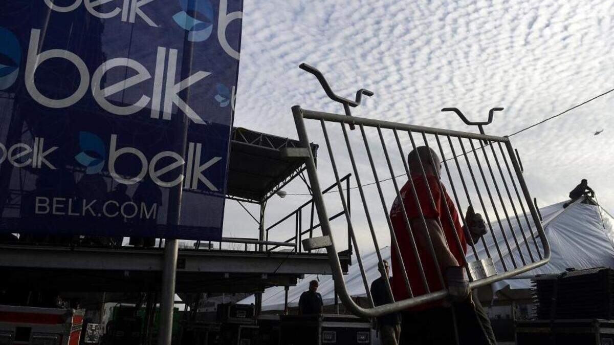 David Propst, with national Rent-A-Fence, totes a barricade while other workers set up the stage and adjoining tents. On Tuesday, Dec. 29, 2015 workers set the stage rigging for Carrie Underwood's concert prior to Wednesday’s Belk Bowl.