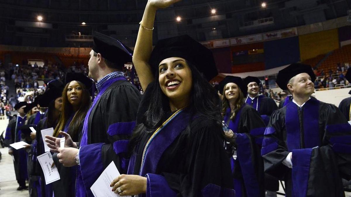 Priya Patel waves to family and friends at the beginning of commencement exercises for the Charlotte School of Law. About 320 hooded students graduated on May 17, 2014 during Spring commencement exercises from the Charlotte School of Law at Bojangles Coliseum. The keynote speaker was Judge Albert Diaz of the 4th Circuit Federal Court of Appeals. Charlotte Law’s first graduating class was in 2009.
