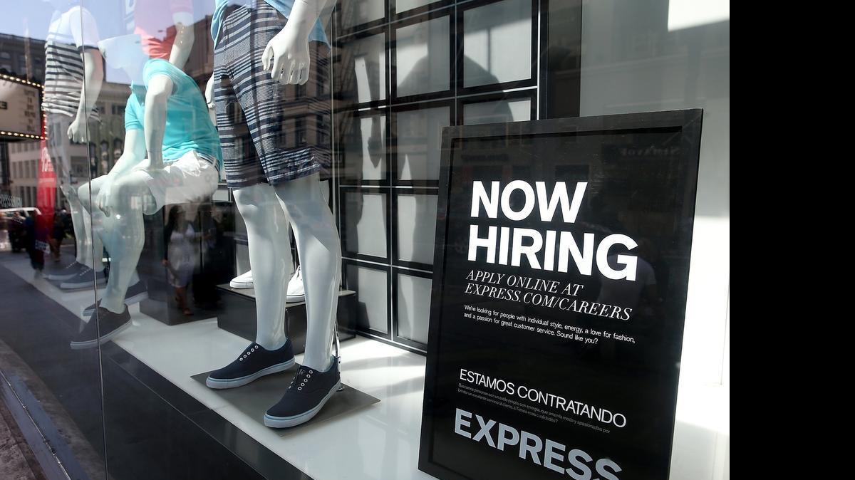 
A now hiring sign is posted in the an Express store
