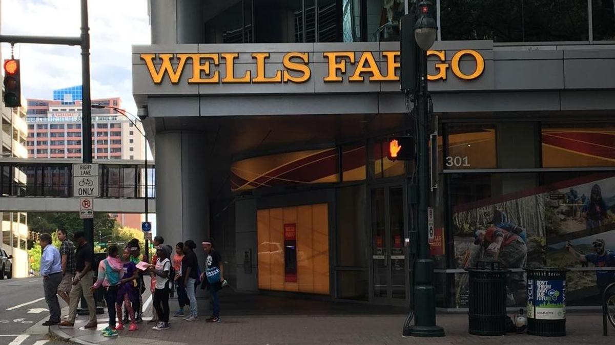 People stand near a Wells Fargo branch at Third and Tryon streets in uptown Charlotte.