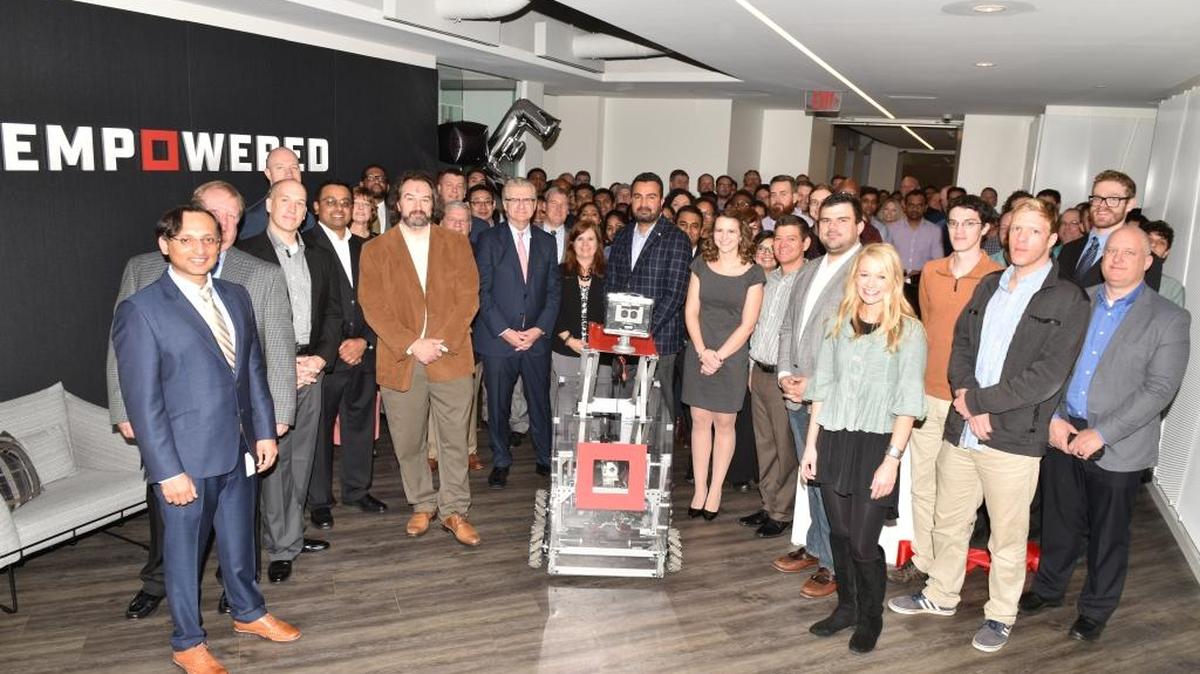 Empowered employees along with a robot created by grade school students from grades K-12 from Queen City Robotics take part in Thursday’s ribbon cutting ceremony for Empowered's new office space in Charlotte. (PRNewsfoto/Aflac)