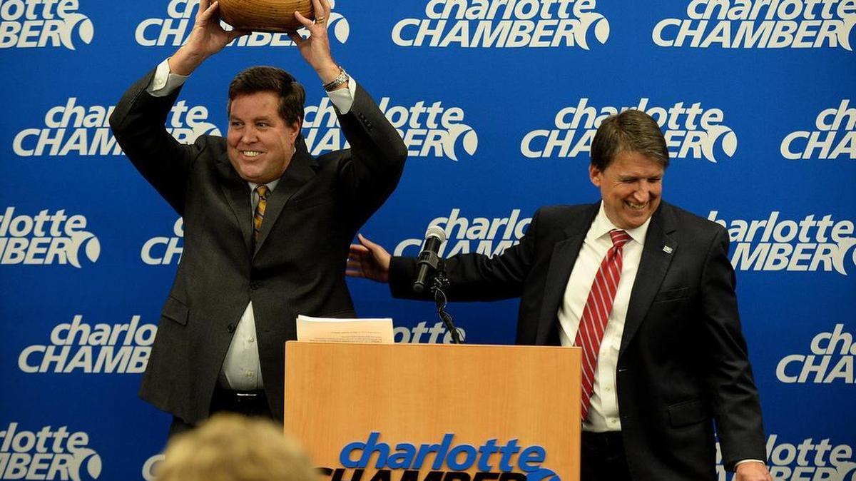 John McCabe, left, senior vice-president of Global Operations at PayPal, holds up a wooden bowl (made by an artist from a tree struck by lightning outside the state capitol), presented to him by Gov. Pat McCrory.