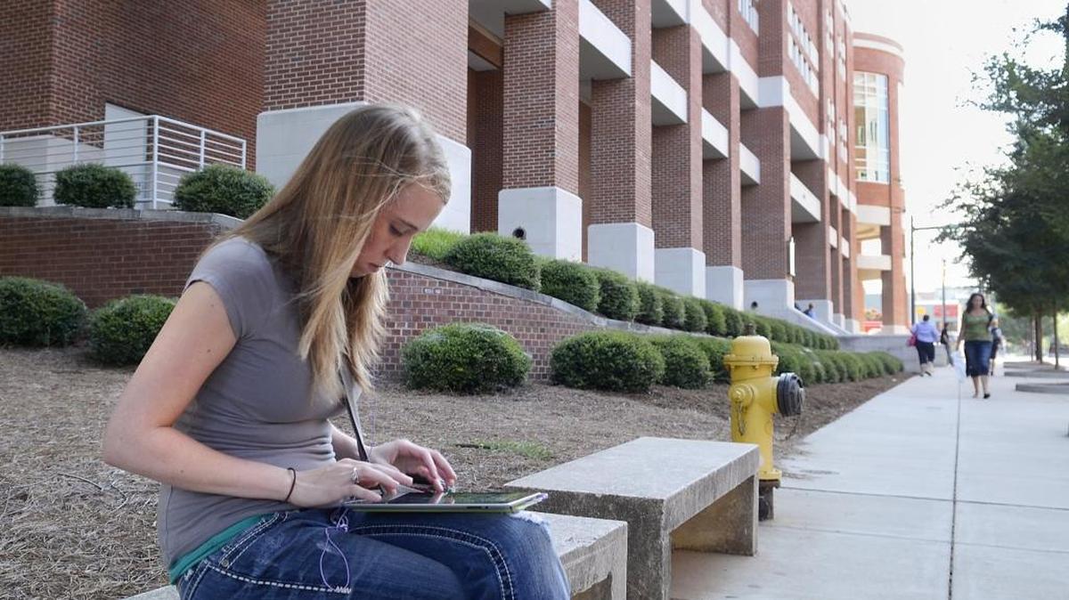 A student works on her tablet along Elizabeth Ave. at CPCC’s Central Campus in an August 2013 file photo.