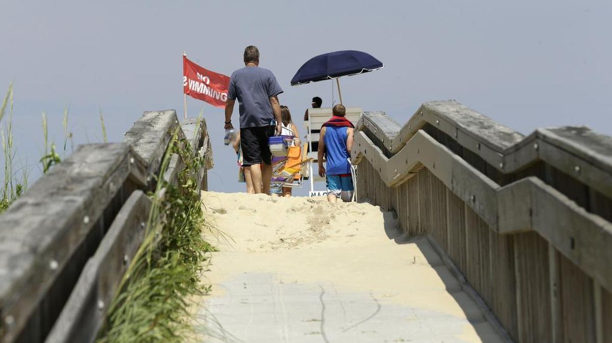 
Vacationers walk across the dunes to the beach after Hurricane Arthur passed through the Outer Banks in Nags Head on July 4, 2014. Visitor spending generated $1.02 billion in 2014 in Dare County, according to state figures released Tuesday. 
