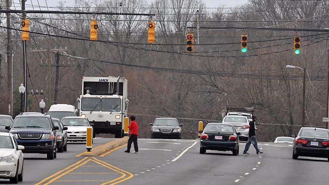 Pedestrians cross West Blvd. near Remount Road. Area residents say their community lacks grocery stores.