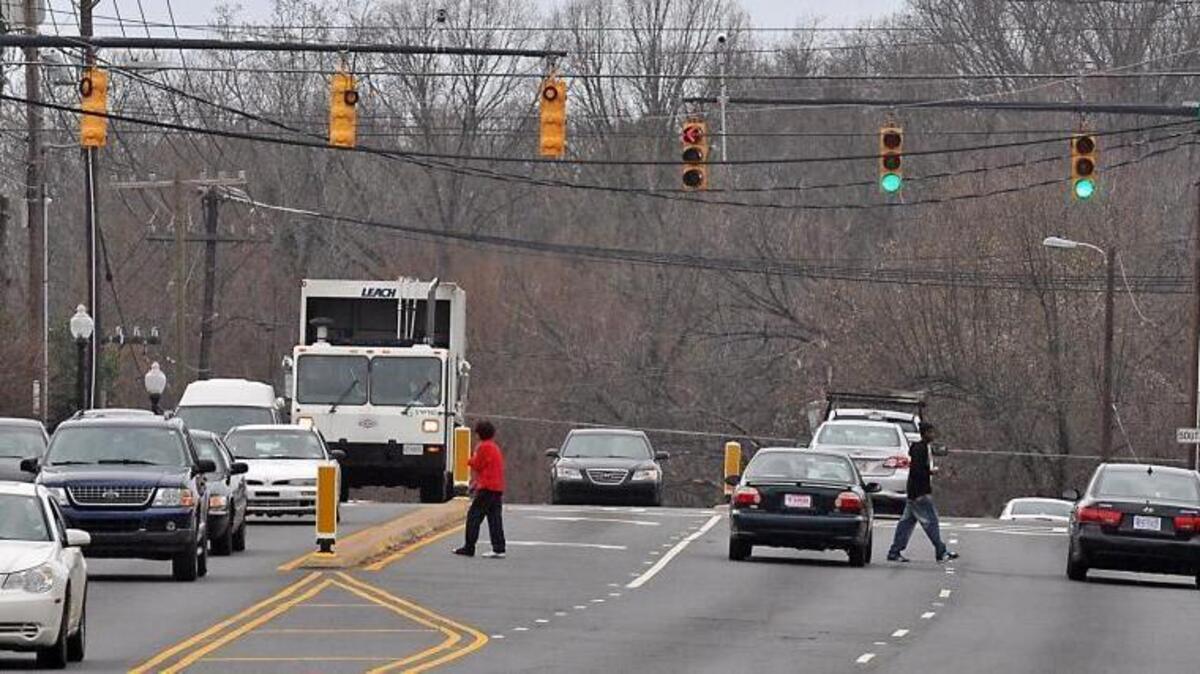 Pedestrians cross West Blvd. near Remount Road. Area residents say their community lacks grocery stores.