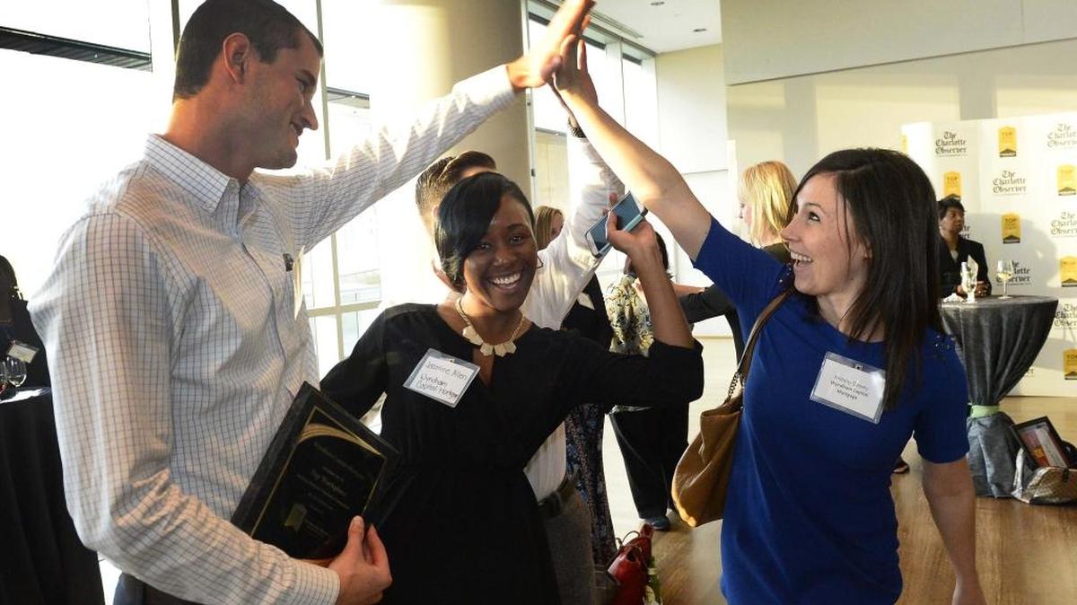 From left: John Eite, Jasmine Allen and Brittany Dewey with Wyndham Capital Mortgage high-five each other after receiving first place in the midsize companies division during the Top Workplaces reveal event held at the Mint Museum on Sept. 23, 2015.