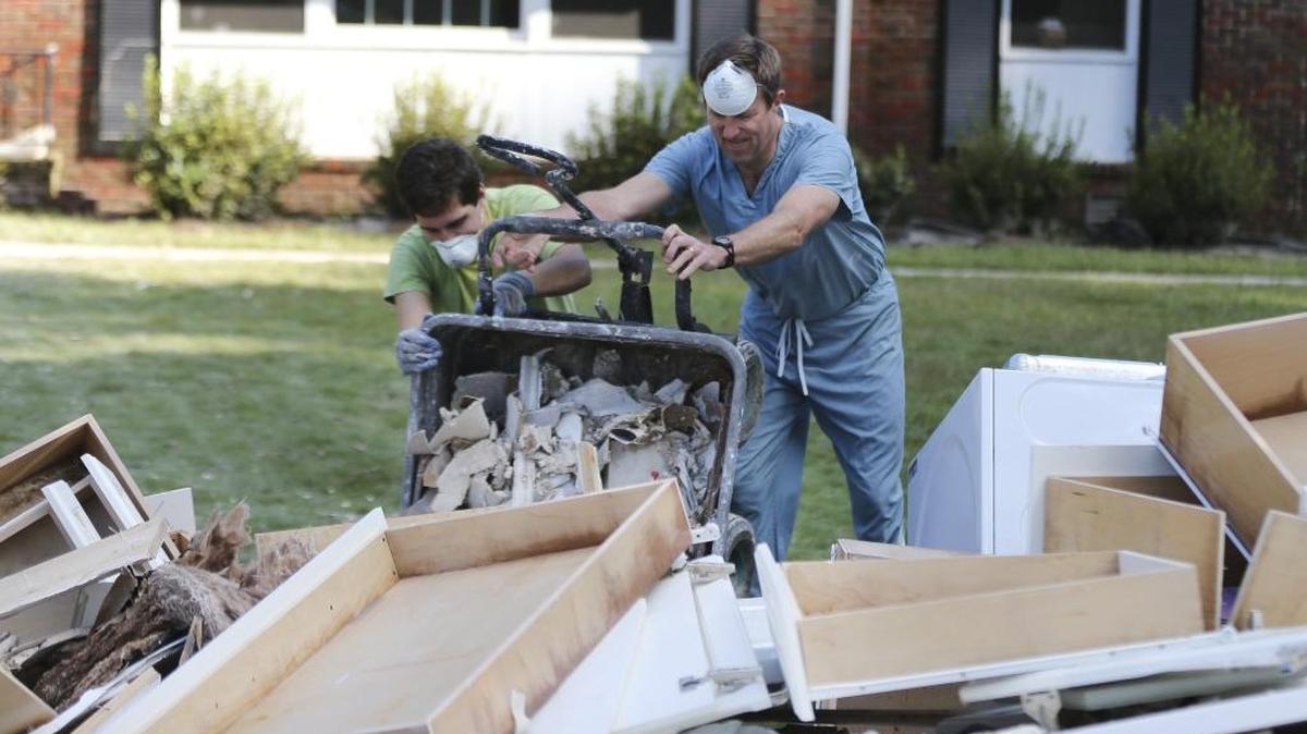 
Ryan Potane, left, and Frank Voss dump a load of debris on the street as they help a neighbor clean his flood-damaged home Thursday in Columbia. 
