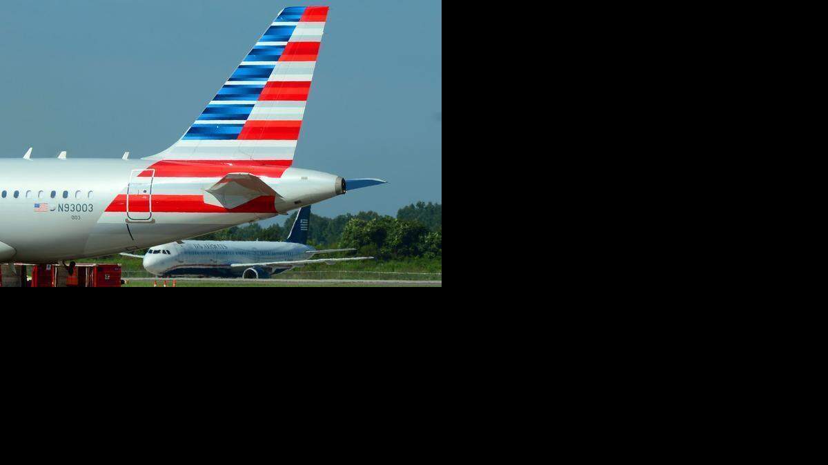 
American and US Airways jets taxi on the tarmac at Charlotte Douglas International Airport in August 2014. The two airlines will combine their loyalty programs on March 28, 2015, about 15 months after merging to create the world’s biggest airline by traffic. 
