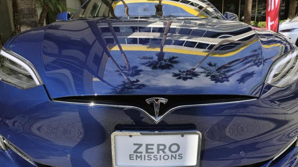 In this file photo, palm trees are reflected on the hood of a Tesla Model S on display in downtown Los Angeles.